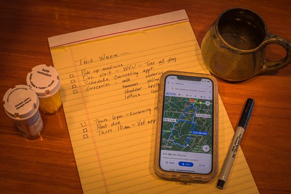 notepad with cellphone map, pen, pill bottles, mug