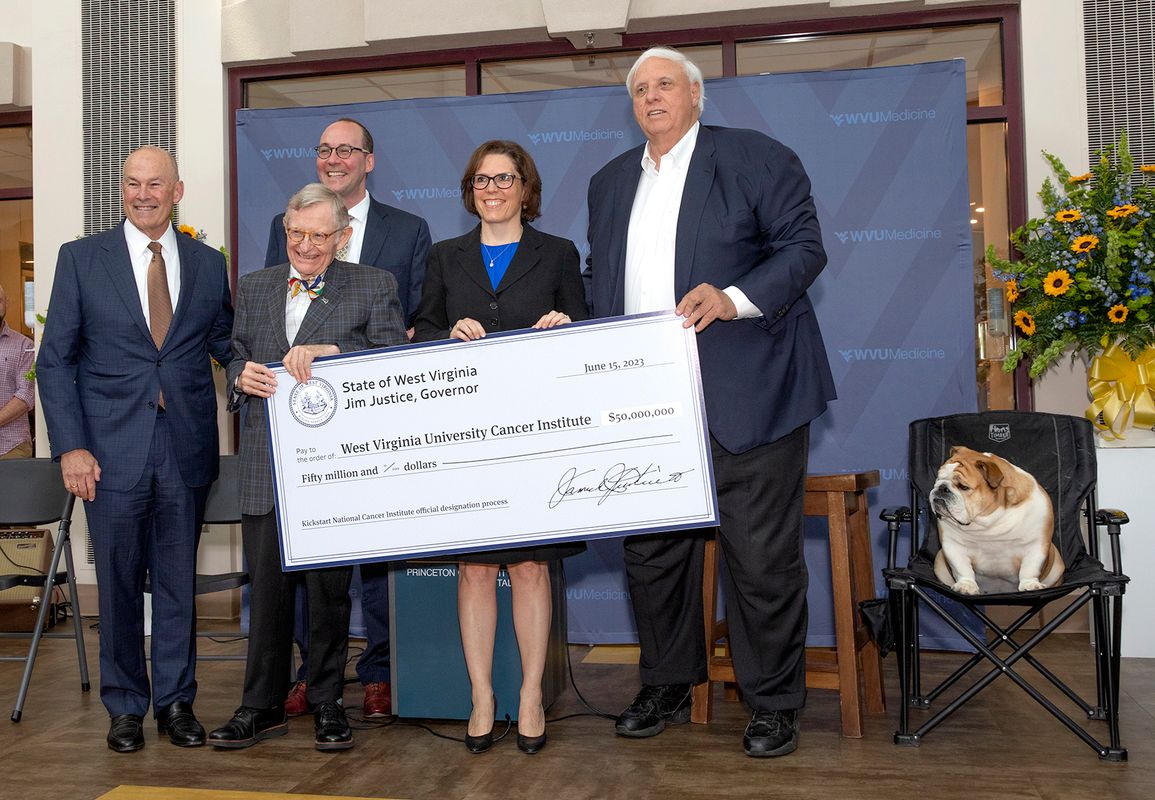 WVU President poses with a large check marking $50 million for the WVU Cancer Institute along with Dr. Clay Marsh, Albert Wright, Dr. Hannah Hazard-Jenkins, Gov. Jim Justice and BabyDog.