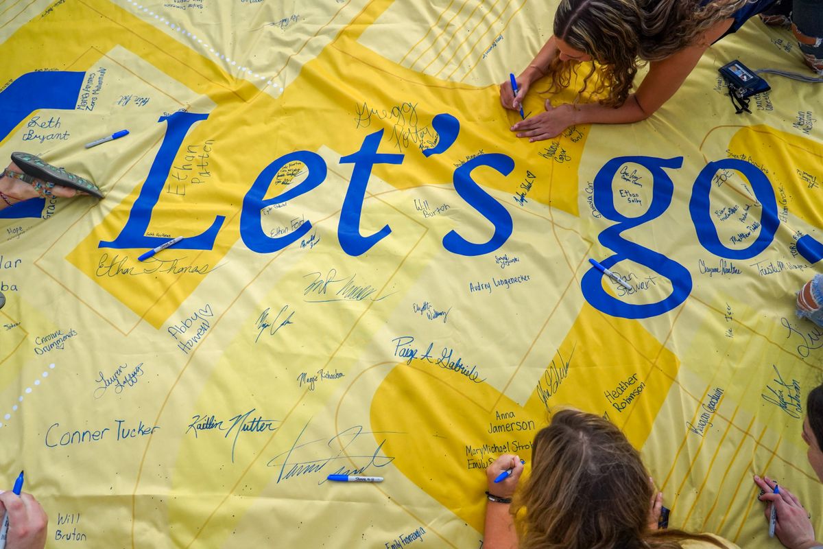 People signing a yellow flag that reads 