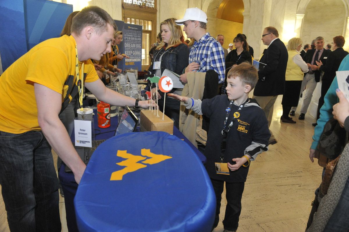 Young man interacts with child at a tabling event.