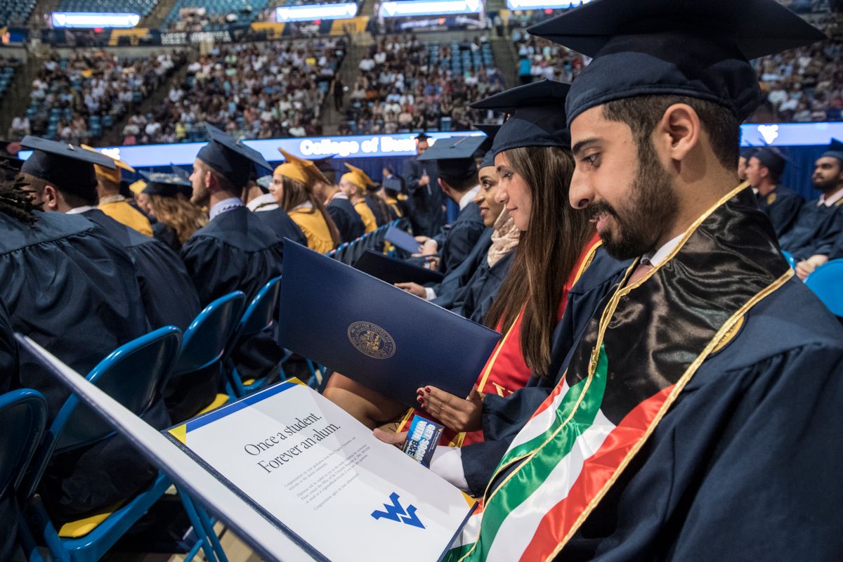 ziz Aldasem reads his diploma after walking during the College of Business and Economics Commencement in the Coliseum.