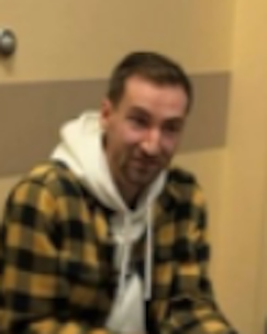 A person is shown wearing a black and gold plaid shirt over a white hoodie.