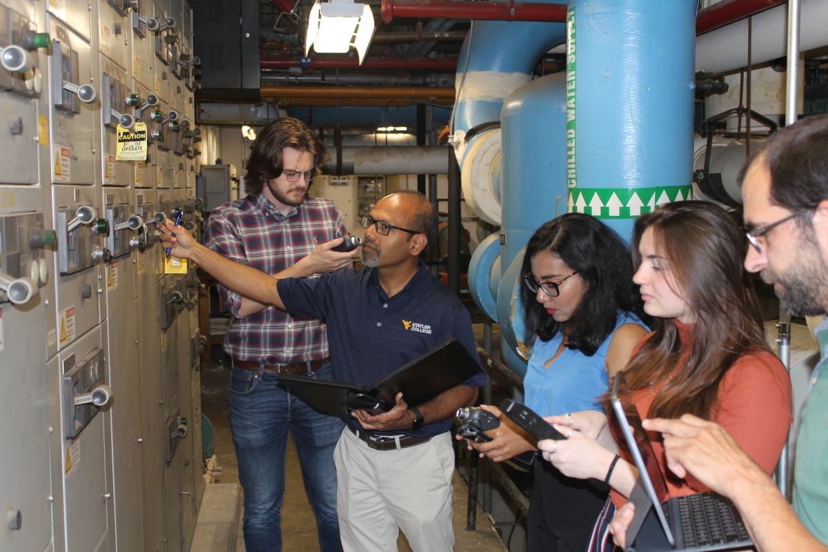 A WVU researcher looks at machines with students. 