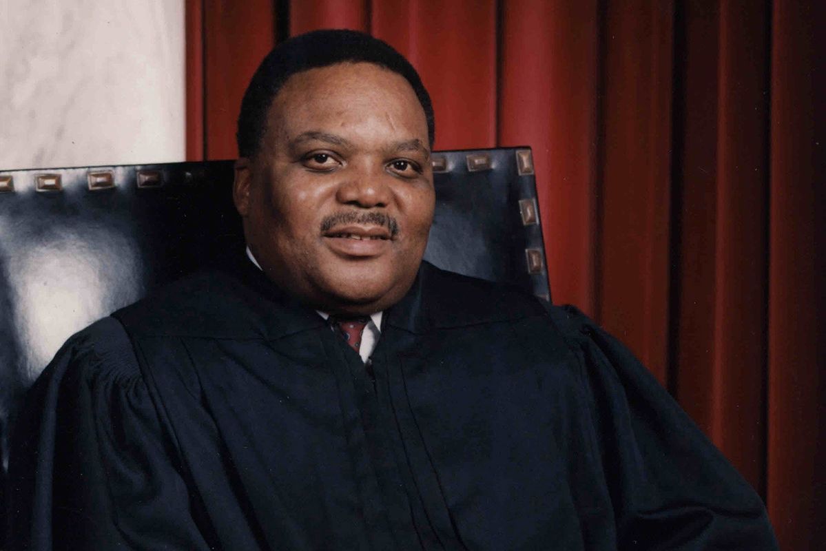 man sits in black chair in black judge's robe