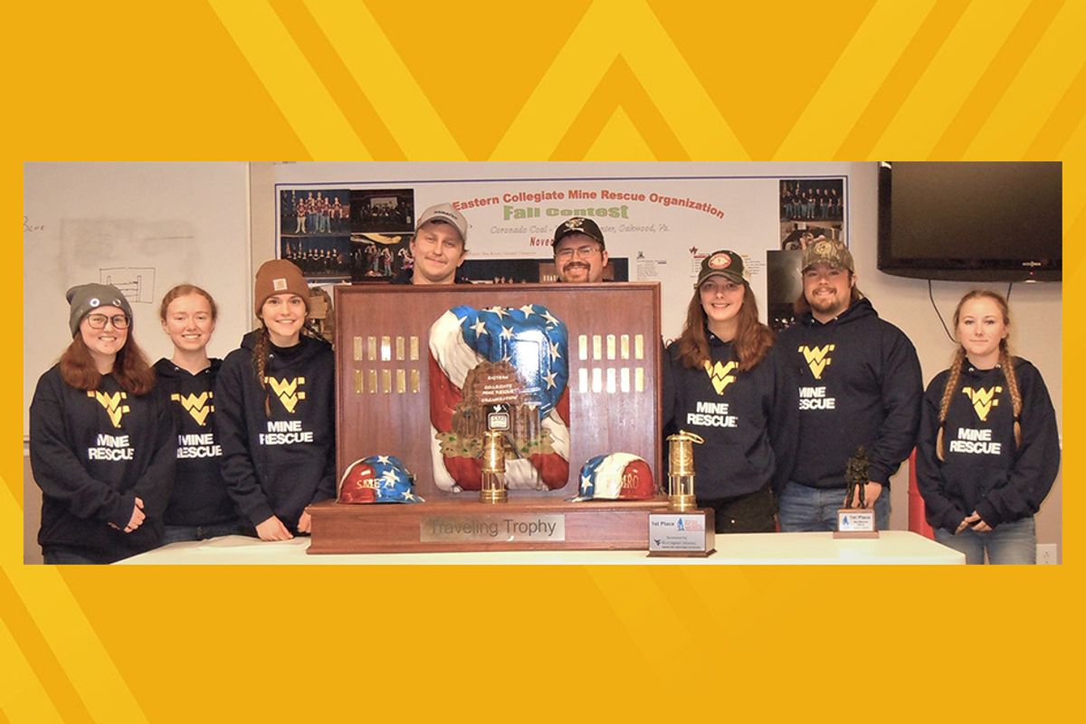 A group of college students stand behind an award; the photo is on a gold background