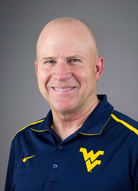 Headshot of WVU professor and forest resources speciality Dave McGill. He is middle-aged, bald, smiling, and wearing a navy blue WVU golf shirt. 