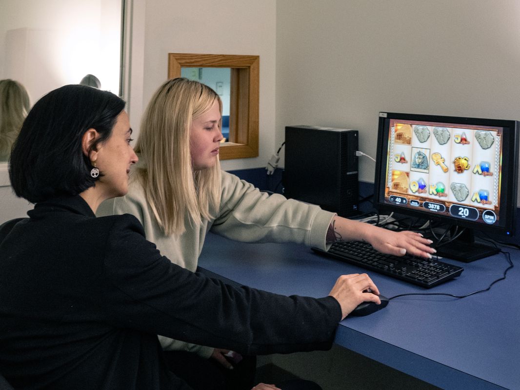 A picture of two female researchers working on a computer screen. One researcher, which shoulder length black hair, commands the mouse while the other with blonde hair, is motioning towards the keyboard. 