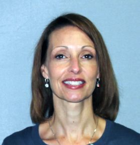 Headshot of WVU employee Penny Lipscomb. She is pictured in front of a blue background and she's wearing an emerald green shirt. She has shoulder length light brown hair. 