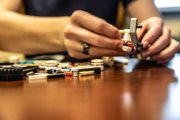 A pair of hands assembling Lego pieces.