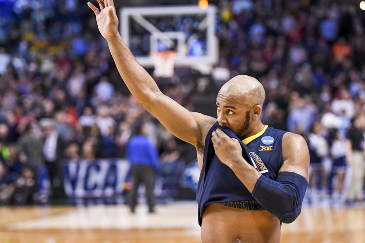 WVU basketball player wiping mouth with jersey on court