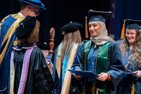 woman walks across the graduation stage