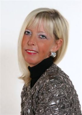 photo of blonde woman facing left wearing shiny gray-ish jacket and black turtleneck