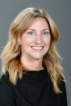 Headshot of WVU Nursery School Director Ashley Martucci. She is pictured in front of a gray background wearing a black blouse. She has long, blonde hair. 