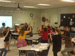 classroom children standing, raising arms
