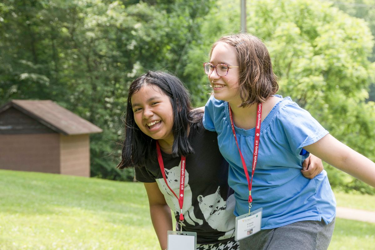 Two young girls smile and embrace at 4-H camp