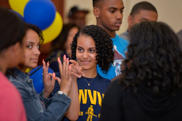 Young woman in WVU shirt stands in group of other young people