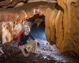 A woman looks at a cave formation in artificial lighting