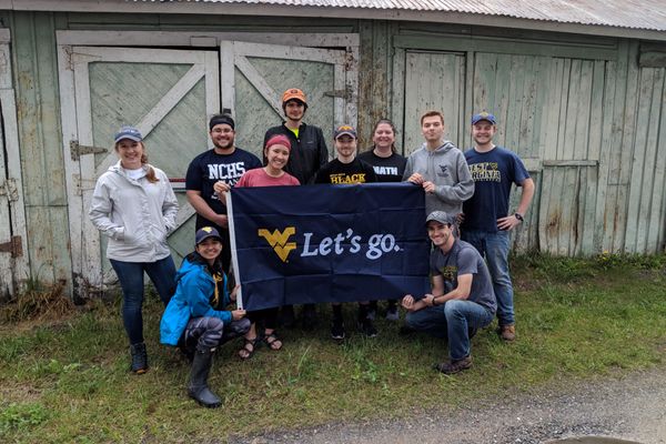 A group of WVU engineering students stand in front of an old building holding a 