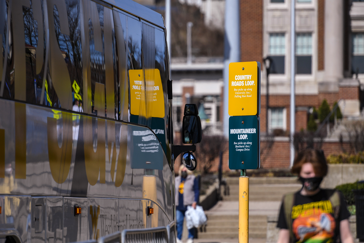 The reflection of traffic signs on the side of a WVU bus.