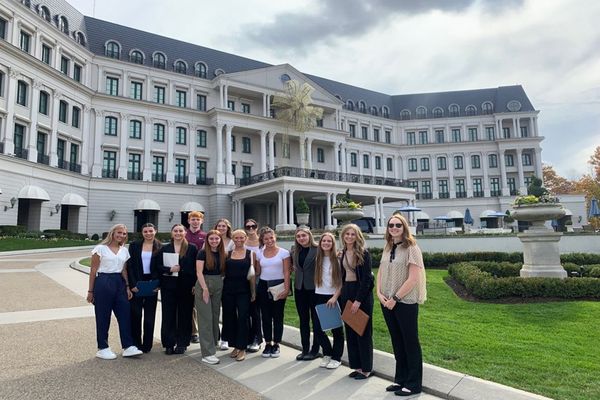 A photograph of several WVU interns standing in front of the huge, white Nemacolin resort. 