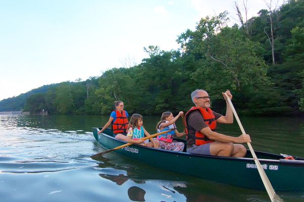 photo of two adults and two children canoeing on a river