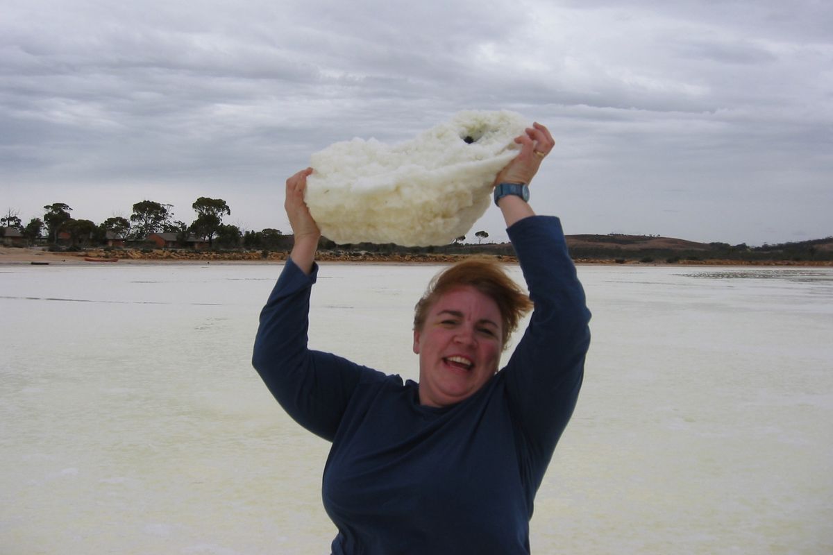 A woman looking happy holding something rick like and white over her head.