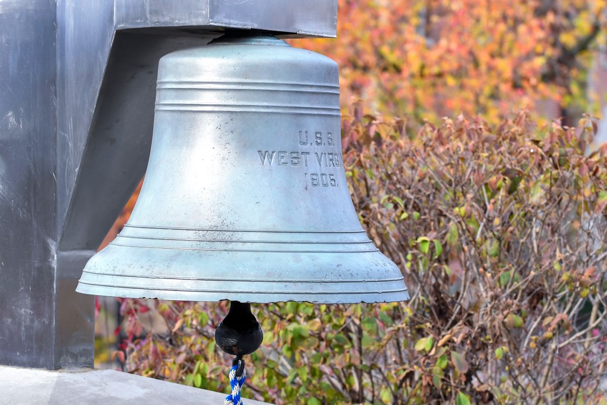 Photo of a silver bell in front of orange and green leaves outside