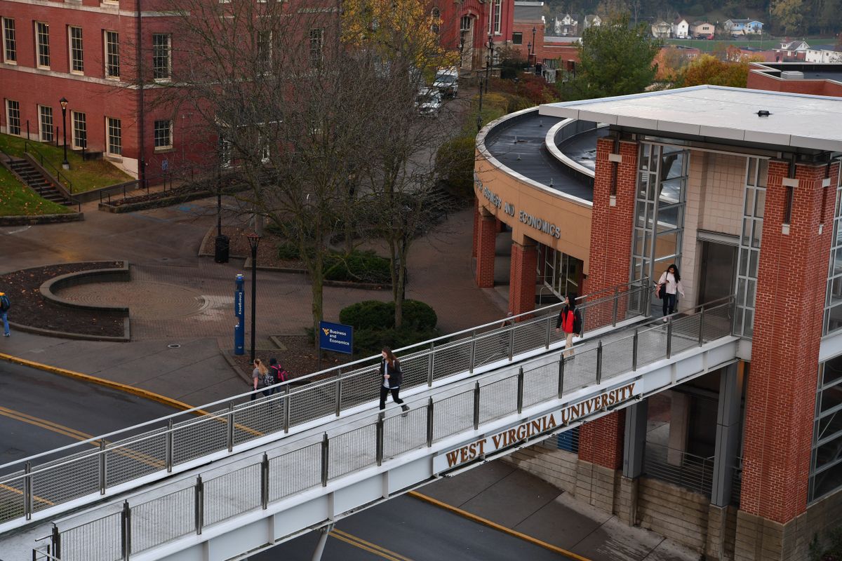Students walk across the pedestrian bridge from the WVU College of Business and Economics.