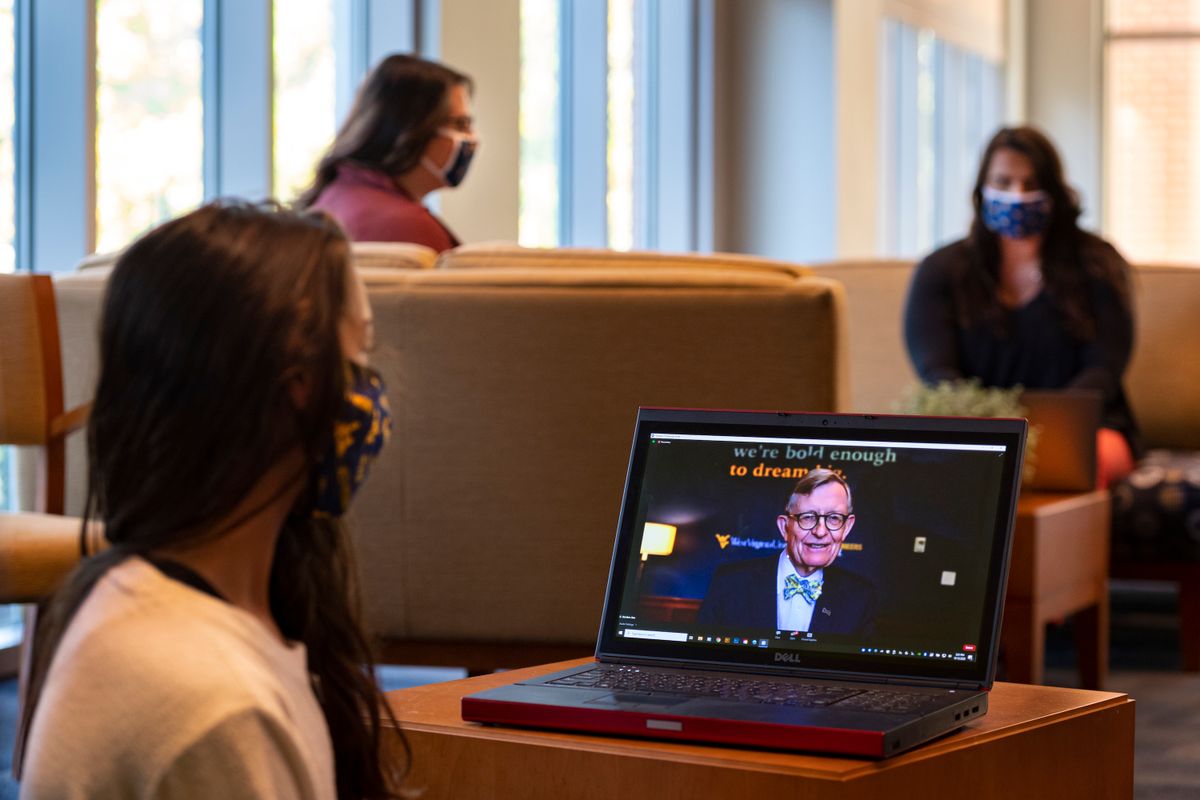 students watch a man speaking on a computer screen