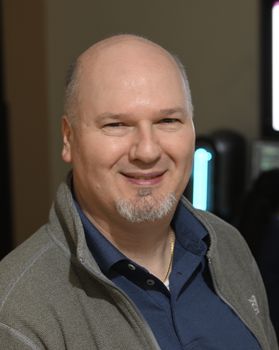 Headshot of WVU professor Gianfranco Doretto. He is bald with a gray beard and is wearing a navy blue shirt with a gray jacket. 