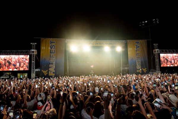 The FallFest stage is shown against a night sky with hundreds of phones raised in the air.