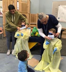adults work with kids in protective medical clothing