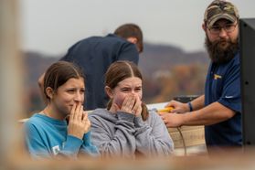 Two students cover their mouths while reacting to the Pumpkin Drop. A University worker is on the right side of the shot.