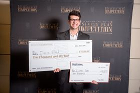 Young man wearing glasses holds large checks