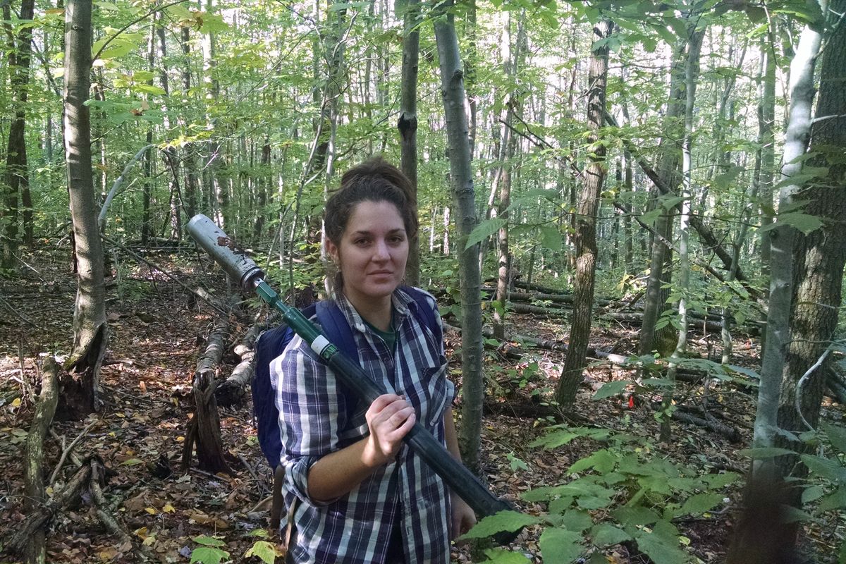 photo of young woman in the woods with soil sampler