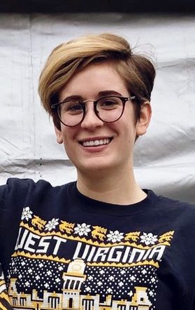 Headshot of young woman with short blonde hair and glasses wearing a navy blue WVU sweatshirt