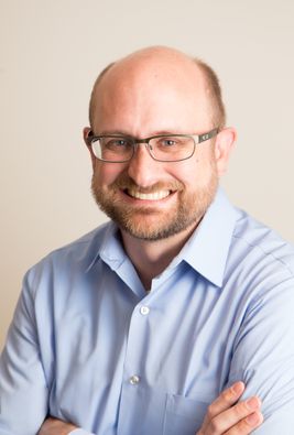 Headshot of WVU researcher Chris Scheitle. He is wearing a light blue dress shirt and glasses. He is balding and has a light colored beard. 