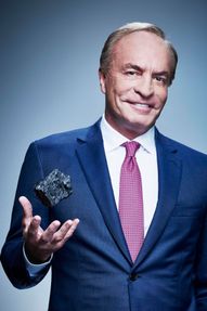 photo of man in suit and tie tossing a lump of coal above his left hand