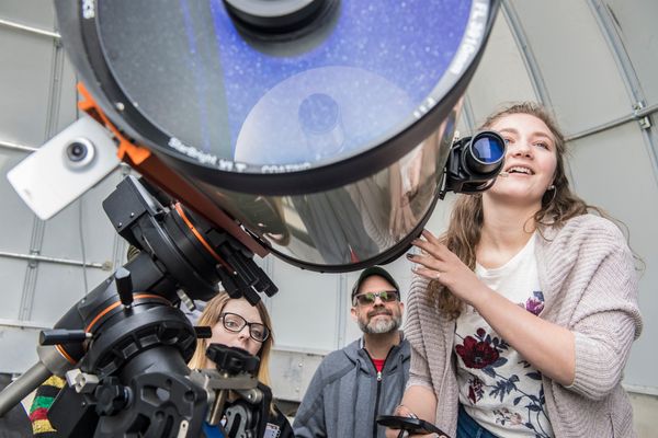 people look through a large telescope