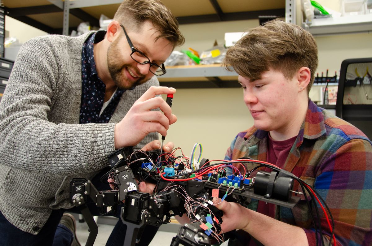 WVU researcher Nicholas Szczecinski works with Clarus Goldsmith on a robot in the lab. 