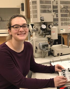 Headshot of WVU student Ellena Gemmen. She is pictured in a lab working with equipment. She is wearing a maroon shirt and has her dark blonde hair pulled back in a pony tail. She is also wearing glasses. 