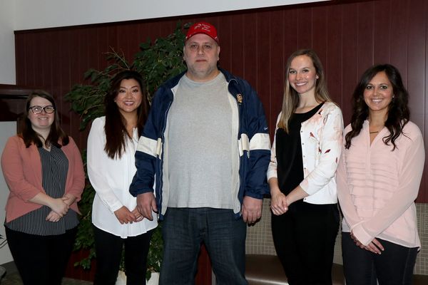 Four female WVU law students standing with man in grey shirt and red hat