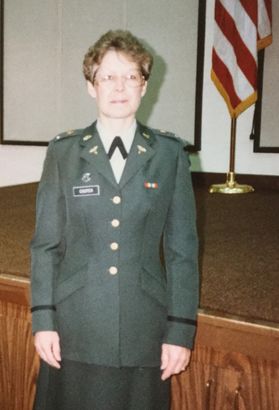 A woman smiles with glasses on and a uniform in a courtroom
