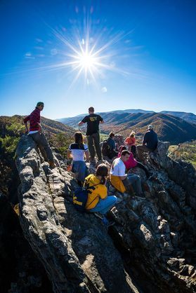 Group of people sitting on rock in front of mountains