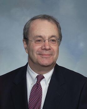 portrait of smiling man wearing glasses, suit and tie