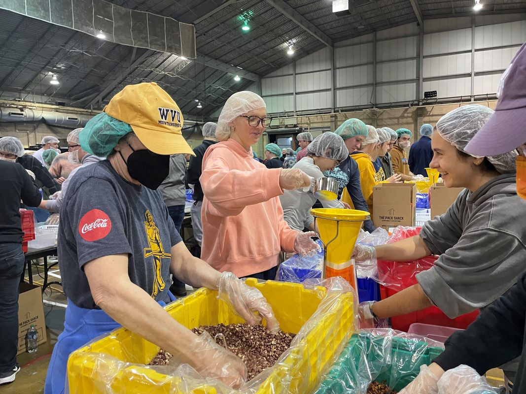 Members of the WVU community gather to volunteer during a meal packing event held in the fall of 2022. Several young people are pictured in the photo sorting food. 