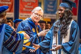 Easter Kith, exercise physiology major in the School of Medicine, is congratulated by Provost and Vice President for Academic Affairs Joyce McConnell as she walks across the platform during December Commencement in the Coliseum Dec. 15, 2018. 