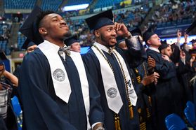 Daxter Miles, Jr., left, and Jevon Carter stand with classmates after singing Country Roads one final time at the Coliseum at the conclusion of the CPASS commencement Friday, May 11, 2018.