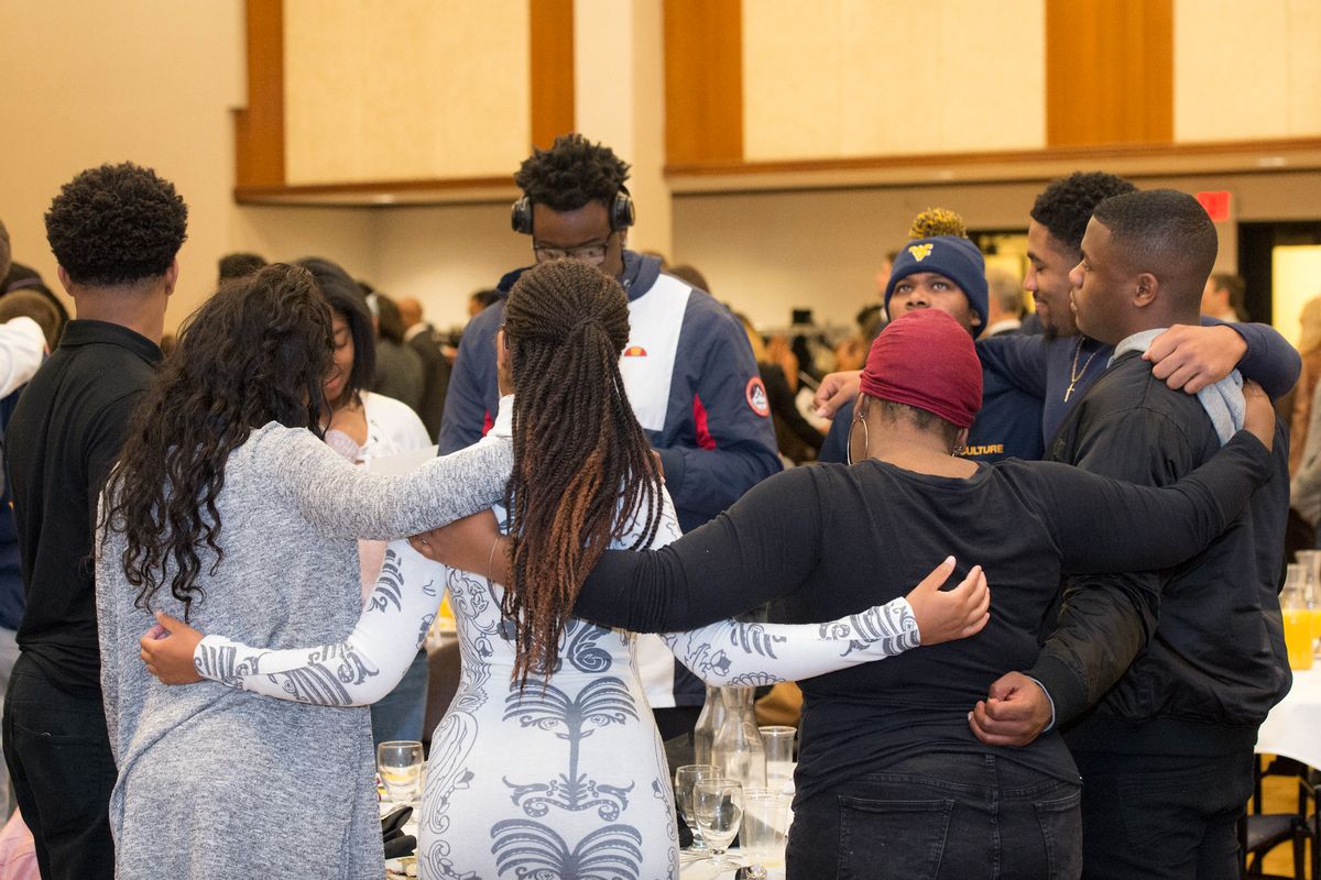 Students, faculty and staff link arms during WVU's 2018 Martin Luther King Jr. Unity Breakfast. 