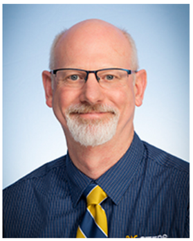 Headshot of Dan Summers, Director of the WVU STEPS simulation lab. He is bald, wearing a blue checked shirt, and a blue and gold striped tie. He is also wearing glasses and has a gray goatee